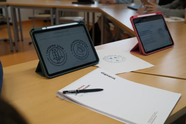 Tablets auf Schultischen zeigen gestaltete Logos und Entwürfe aus der Mediendesign AG.